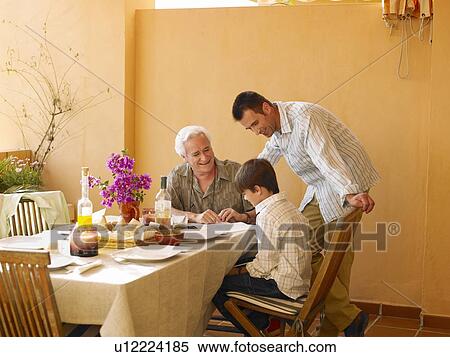 Stock Photography - Boy (8-10) with father and grandfather at dining table on balcony. Fotosearch