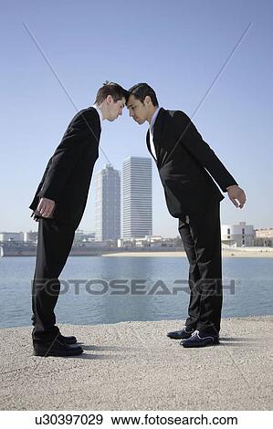 Business men head to head by seafront View Large Photo Image Stock Photo - Business men head to head by seafront. Fotosearch