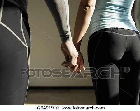 Stock Image - Couple holding hands, rear view, close-up. Fotosearch