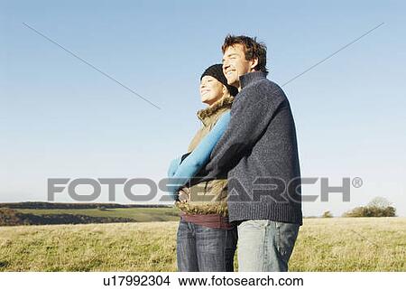 Picture - Embracing couple in countryside. Fotosearch