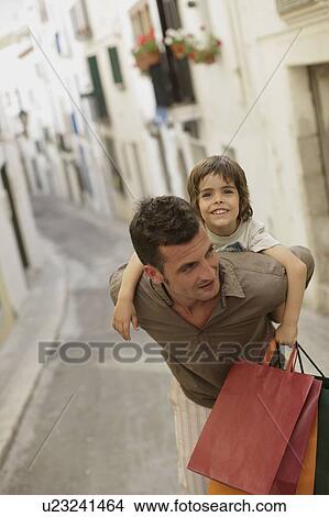 Father carrying son and shopping bags View Large Photo Image Picture - Father carrying son and shopping bags. Fotosearch