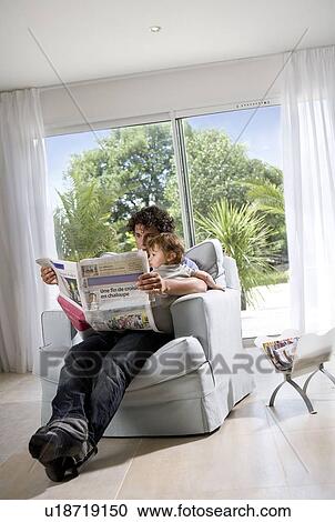 Stock Image - Father reading newspaper with baby. Fotosearch