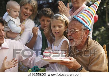 Grandfather blowing out candles at party View Large Photo Image Stock Image - Grandfather blowing out candles at party. Fotosearch