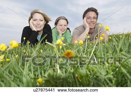Stock Image - Portrait of happy family lying on grass. Fotosearch