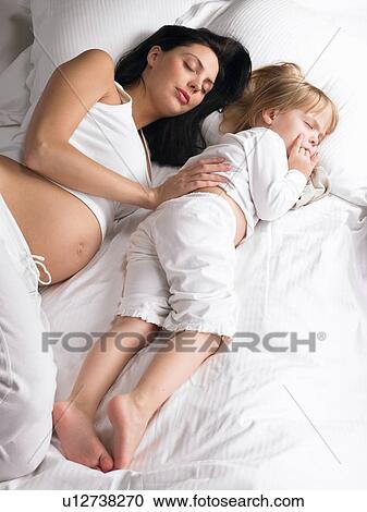 Stock Image - Pregnant woman and daughter sleeping. Fotosearch