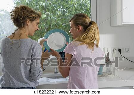 Stock Image - Sisters washing the dishes. Fotosearch