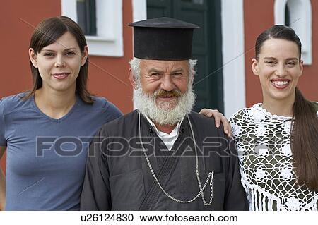 Two young girls and old priest in front of church smiling into camera portrait. View Large Photo Image Stock Image - Two young girls and old priest in front of church smiling into camera portrait.. Fotosearch