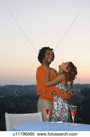 Stock Photography - Young man and woman hugging at sunset. Fotosearch