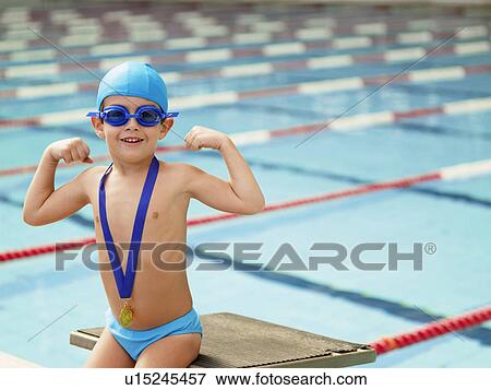 Stock Photo - Boy celebrating medal by swimming pool (portrait). Fotosearch
