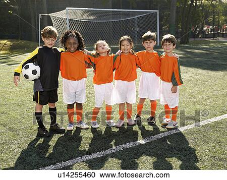 Stock Image - Children standing in soccer field (portrait). Fotosearch