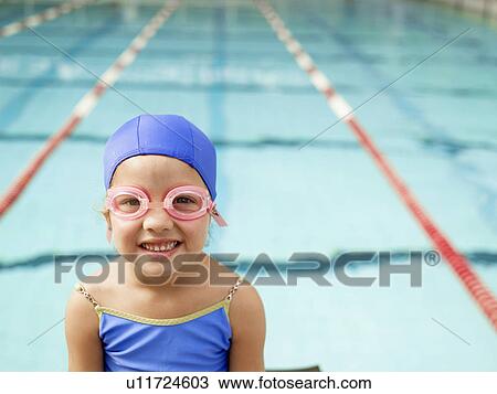 Stock Image - Girl wearing swimming goggles by pool (portrait). Fotosearch