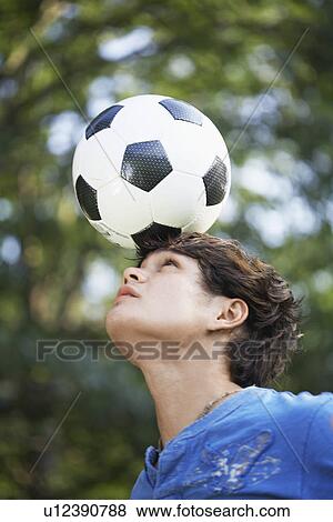 Stock Photo - Teenage boy balancing soccer ball on forehead. Fotosearch