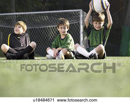 Three boys sitting in soccer field (portrait, low angle view) View Large Photo Image Stock Image - Three boys sitting in soccer field (portrait, low angle view). Fotosearch