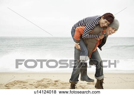 Man giving woman piggyback on beach View Large Photo Image Stock Photo - Man giving woman piggyback on beach. Fotosearch
