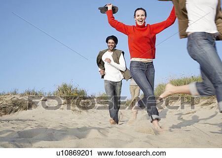 Stock Image - People running on beach (blurred motion, low angle view). Fotosearch