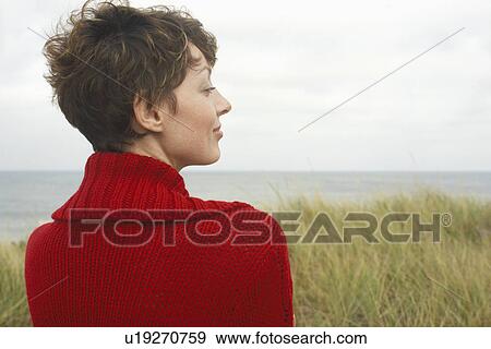 Stock Photo - Woman in cardigan at beach (rear view). Fotosearch