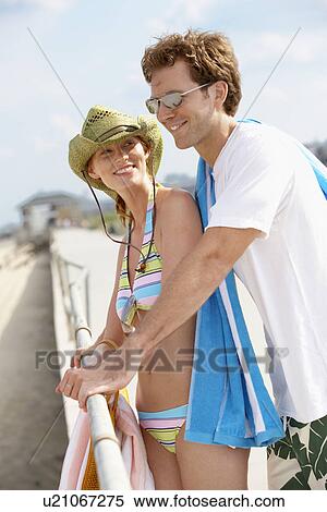 Young couple in beach attire leaning against railings View Large Photo Image Stock Photography - Young couple in beach attire leaning against railings. Fotosearch