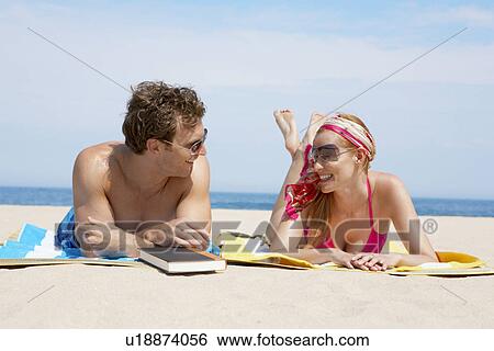 Young couple relaxing on beach mats View Large Photo Image Stock Photograph - Young couple relaxing on beach mats. Fotosearch