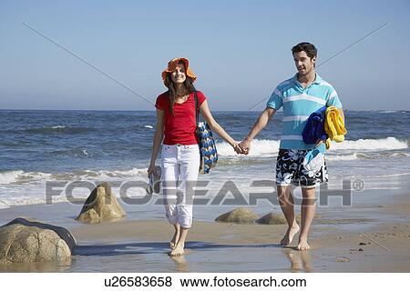 Stock Photo - Young couple walking at beach. Fotosearch