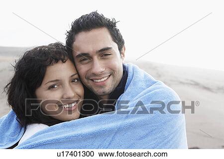 Stock Image - Young couple wrapped in towel (portrait). Fotosearch