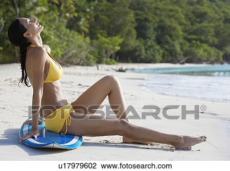 Young woman sunbathing on surfboard at beach, St. John, US Virgin Islands, USA View Large Photo Image Stock Image - Young woman sunbathing on surfboard at beach, St. John, US Virgin Islands, USA. Fotosearch