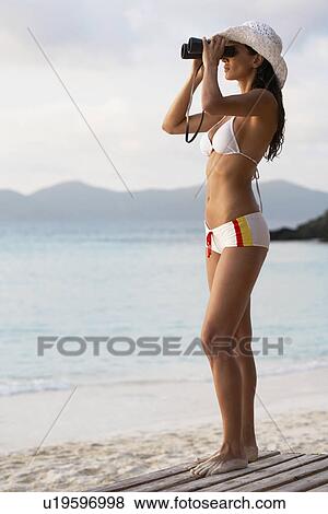 Young woman using binoculars on beach, St. John, US Virgin Islands, USA View Large Photo Image Stock Photo - Young woman using binoculars on beach, St. John, US Virgin Islands, USA. Fotosearch