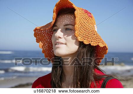 Stock Photo - Young woman wearing hat at beach. Fotosearch