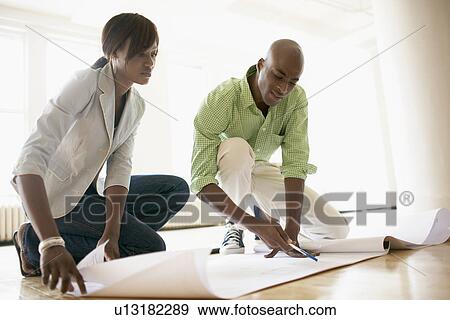 Architects examining blueprints (low angle view) View Large Photo Image Stock Photo - Architects examining blueprints (low angle view). Fotosearch