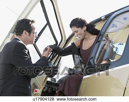 Businessman helping woman to disembark helicopter View Large Photo Image Stock Photo - Businessman helping woman to disembark helicopter. Fotosearch
