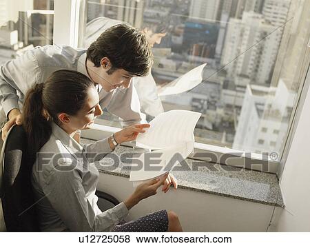 Stock Photo - Businesspeople reading documents by window (high angle view). Fotosearch