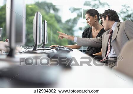 Stock Image - Businesswoman and businessman working on computer. Fotosearch