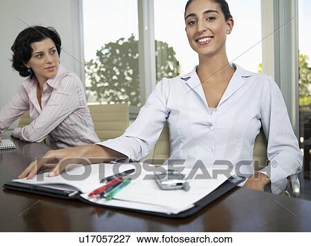 Stock Photo - Businesswomen with file and cell phone (portrait, low angle view). Fotosearch