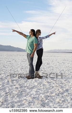Couple standing back to back and pointing to opposite directions in desert View Large Photo Image Stock Photography - Couple standing back to back and pointing to opposite directions in desert. Fotosearch
