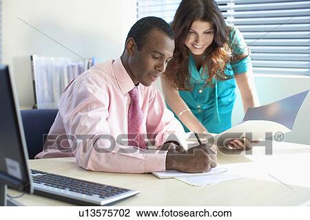 Stock Image - Female and male office worker working together. Fotosearch
