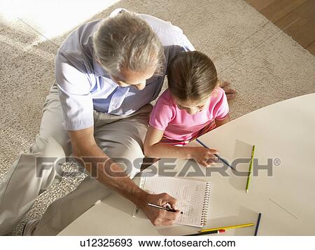 Stock Image - Grandfather and granddaughter drawing with colored pencils (directly above). Fotosearch