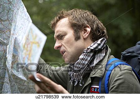 Stock Photo - Male Hiker Reading Map in Forest. Fotosearch