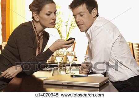 Mid adult couple reading text message in restaurant View Large Photo Image Stock Photography - Mid adult couple reading text message in restaurant. Fotosearch