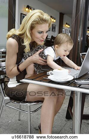 Stock Photo - Mid adult mother showing baby girl laptop computers. Fotosearch