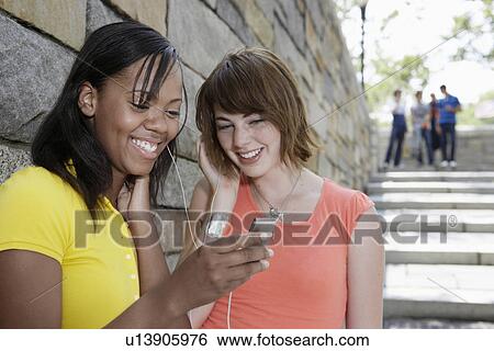 Stock Photograph - Teenage girls sharing MP3 player. Fotosearch