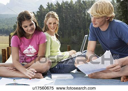Three teenagers working with computer on jetty View Large Photo Image Stock Photography - Three teenagers working with computer on jetty. Fotosearch