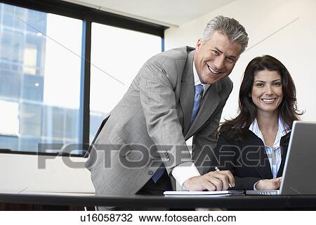 Stock Image - Two businesspeople working on laptop. Fotosearch