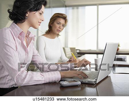 Stock Image - Two businesswomen using laptop computer. Fotosearch