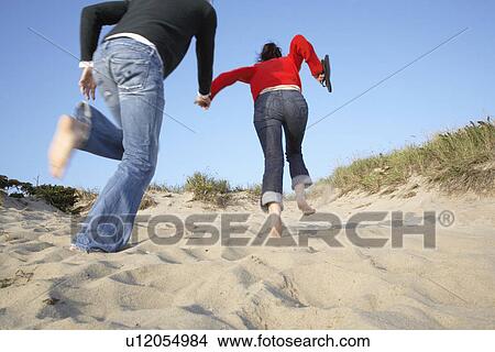 Picture - Two people running on sand (low angle view). Fotosearch