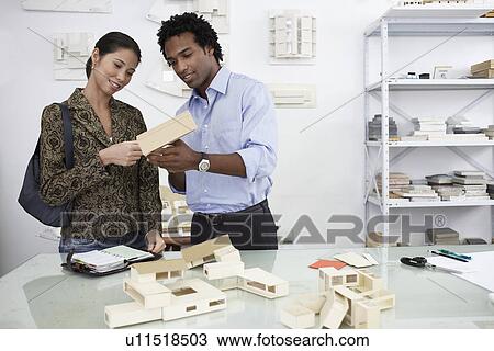 Stock Image - Woman and man examining model houses. Fotosearch