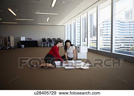 Stock Photo - Women examining blueprints on floor. Fotosearch