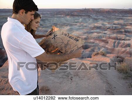 Young couple looking at treasure map on barren landscape View Large Photo Image Stock Image - Young couple looking at treasure map on barren landscape. Fotosearch