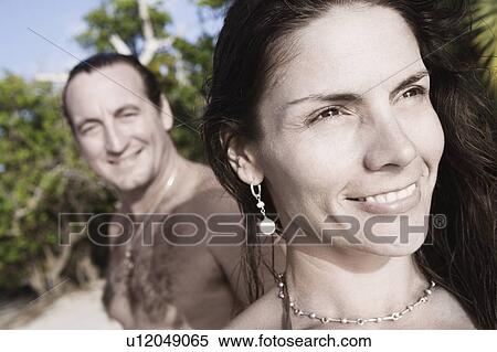 Stock Photography - Close-up of a mid adult woman smiling with a mid adult man standing in the background. Fotosearch