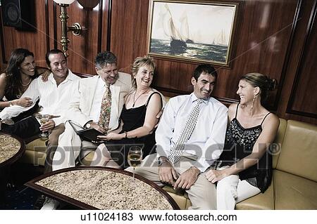 Stock Image - Group of people sitting on a couch and smiling in a sailing ship. Fotosearch