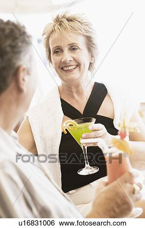 Mature woman and a senior man holding glasses of cocktail and smiling View Large Photo Image Stock Photograph - Mature woman and a senior man holding glasses of cocktail and smiling. Fotosearch