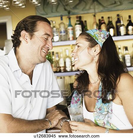 Stock Photography - Mid adult couple at a bar counter and smiling. Fotosearch